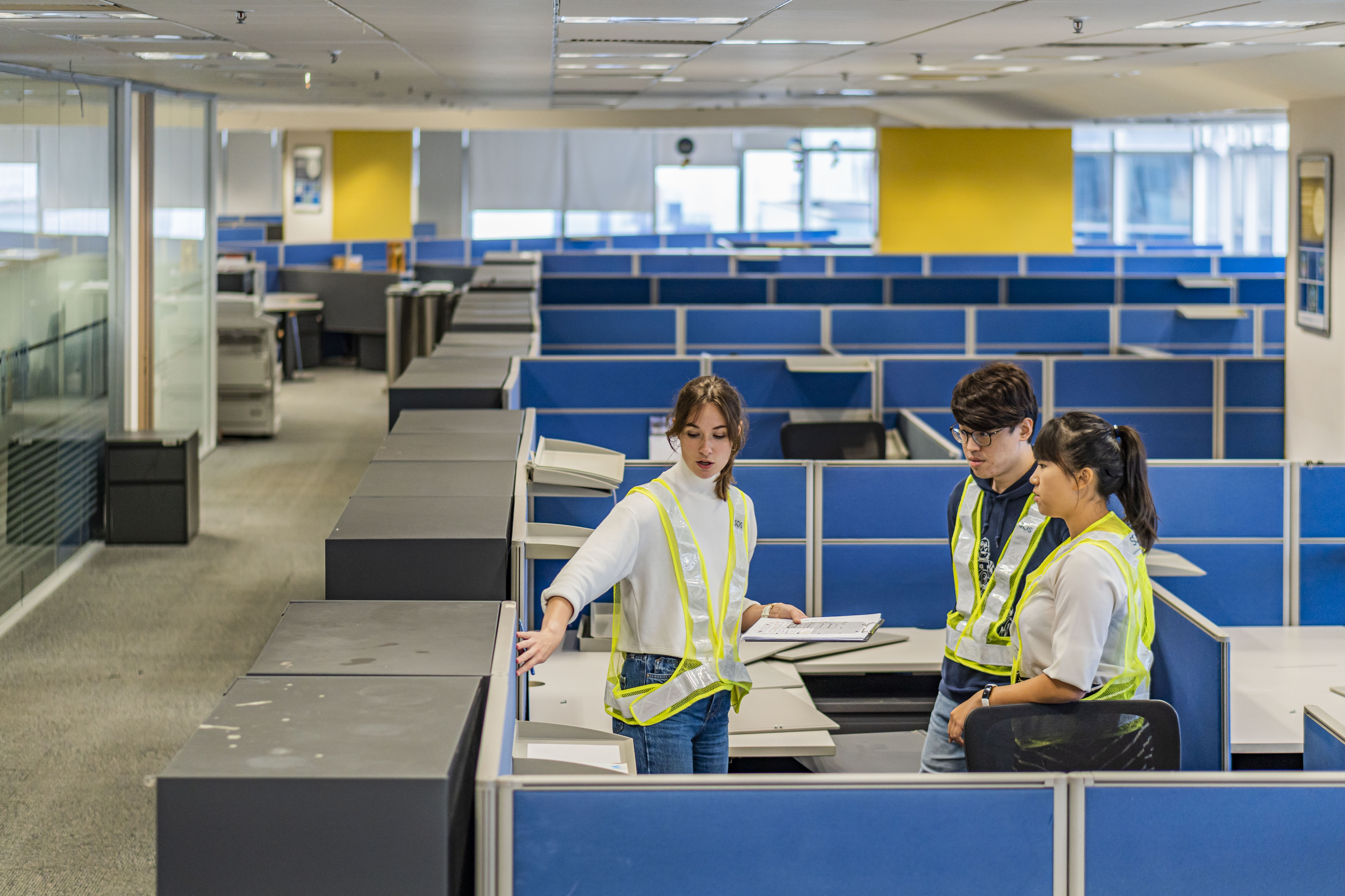 Three members of the Sustainable Office Solutions team conduct an inventory audit in an open office